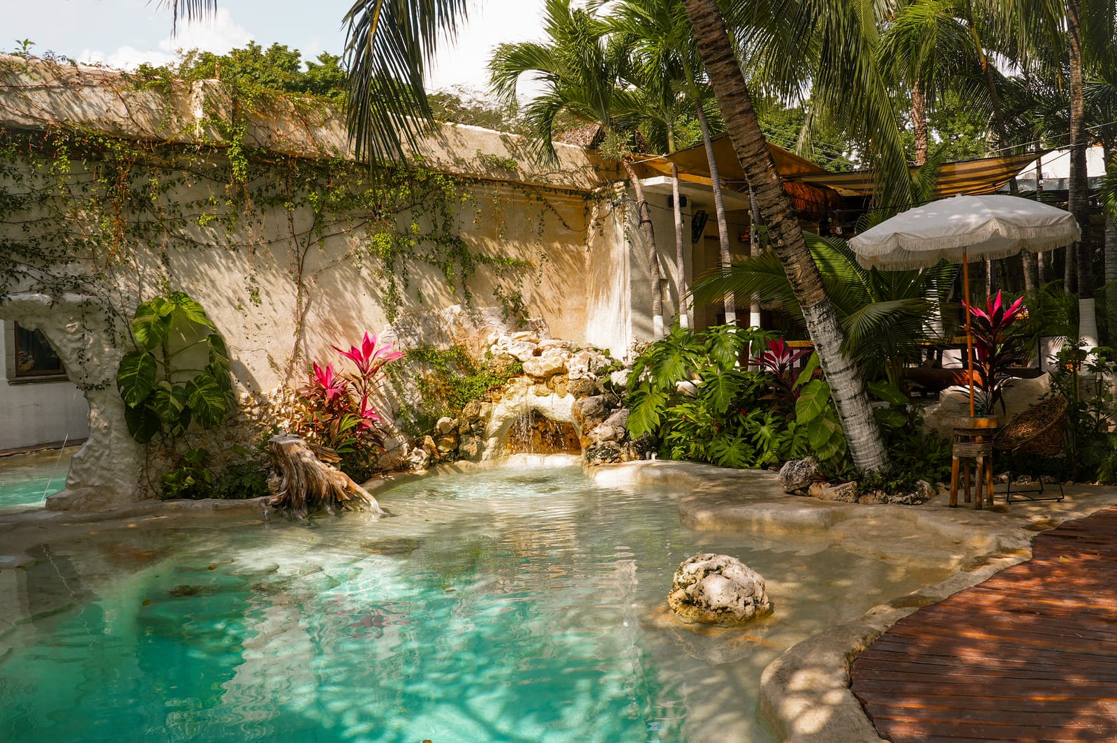 Alberca tipo cenote con cascada rodeada de selva en Mezcal Hotel Boutique