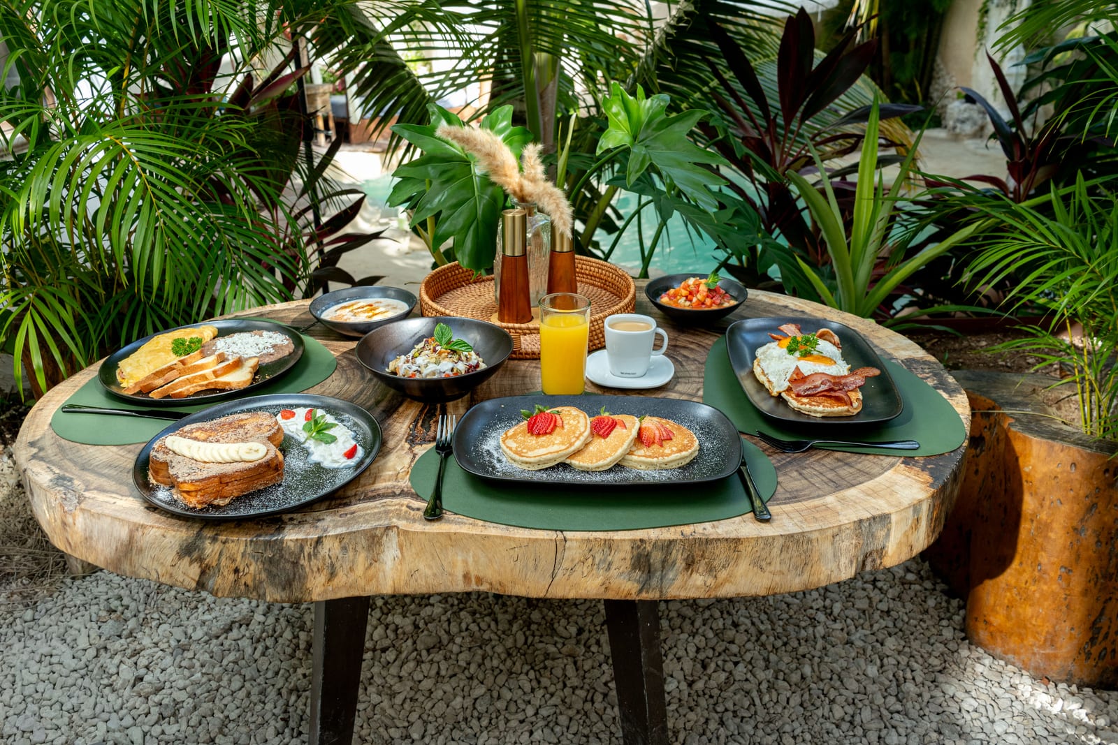 Mesa de desayuno de MERO 18 en el jardín: hotcakes, pan francés y jugos